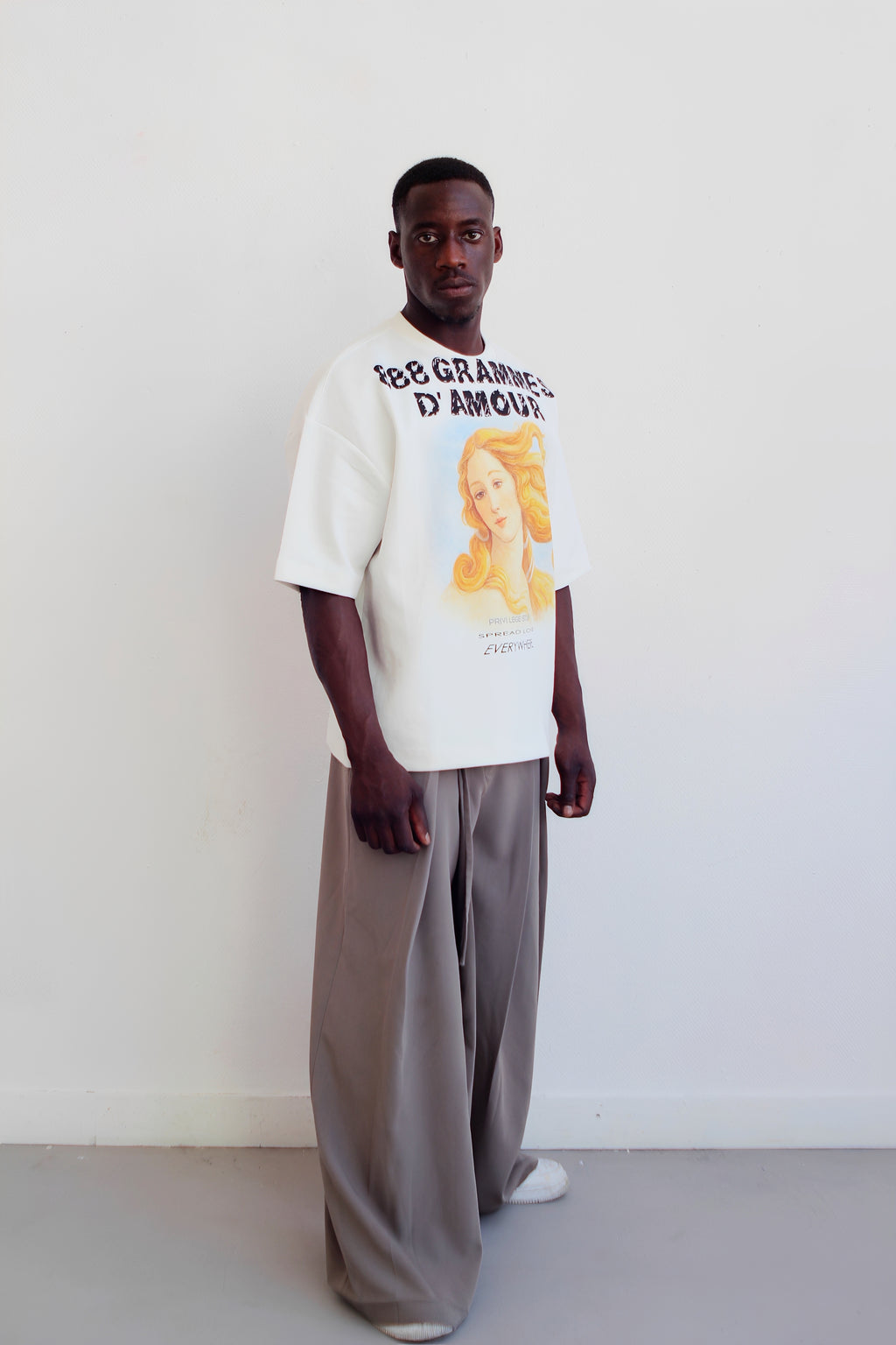 T-shirt 888 Grammes d'Amour blanc porté de face avec un pantalon gris