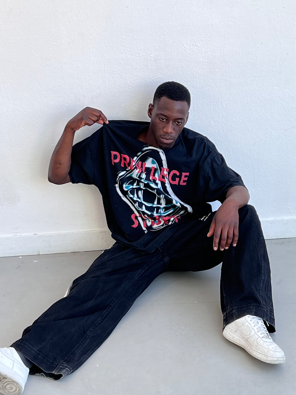 T-shirt World Map noir porté assis, visuel globe chromé sur le devant