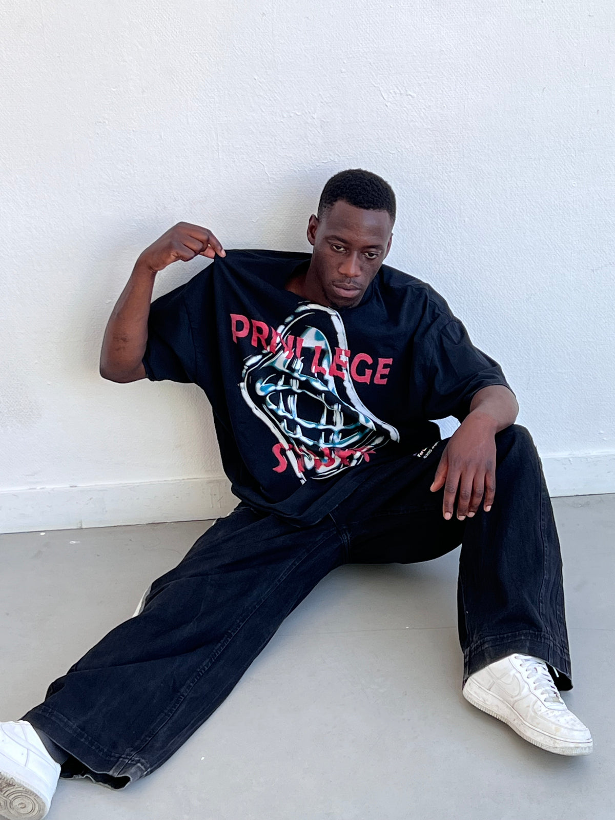 T-shirt World Map noir porté assis, visuel globe chromé sur le devant