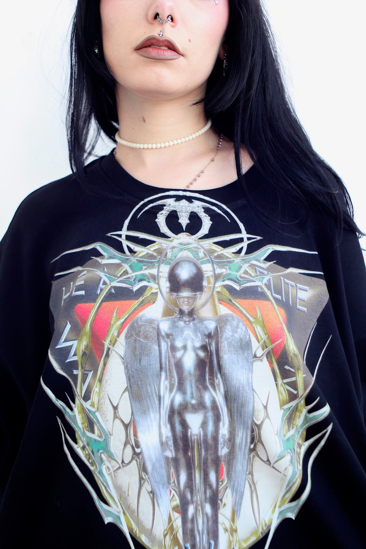 Gros plan du devant du t-shirt Cyborg : figure chromée ailée dans un cadre épineux